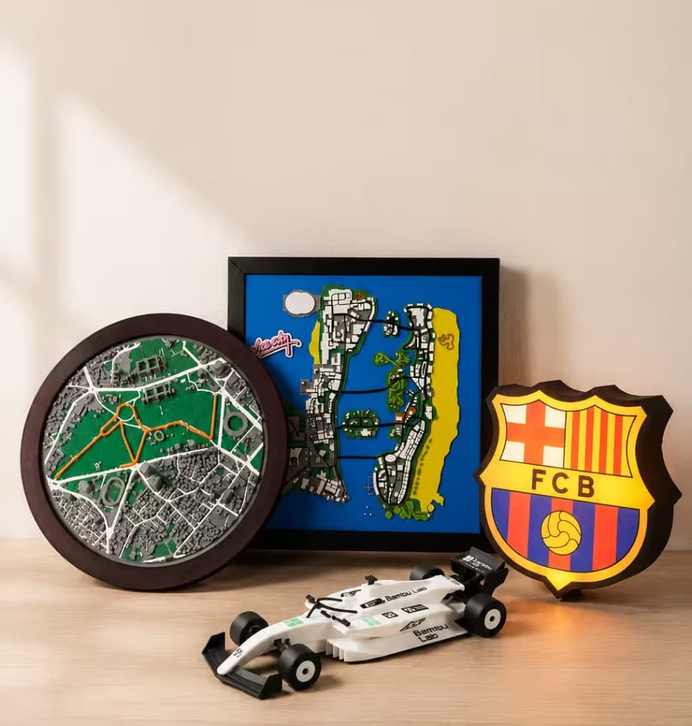 A curated shelf of TwoFold relief maps and motorsport collectibles